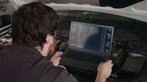 Mechanic Using Laptop to Diagnose Car Engine