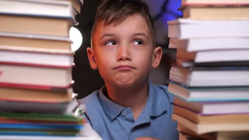a Sad Boy Looks at a Stack of Books and Doesn't Want to Do His Homework