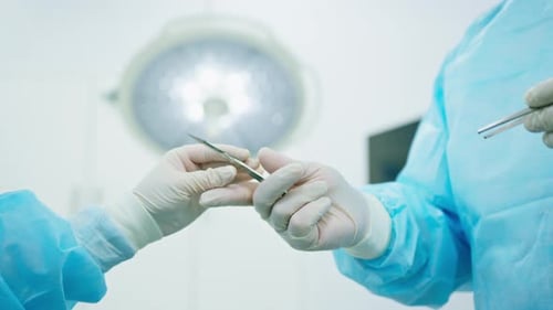 nurse or surgeon in sterile glove holding scalp surgical instruments in hand during surgery close-up