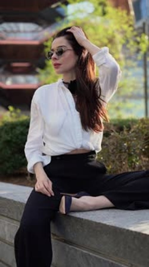 Confident Woman in Sunglasses Poses in Urban Setting with City Background