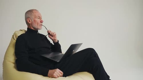 Senior Man with Laptop Relaxing in Beanbag