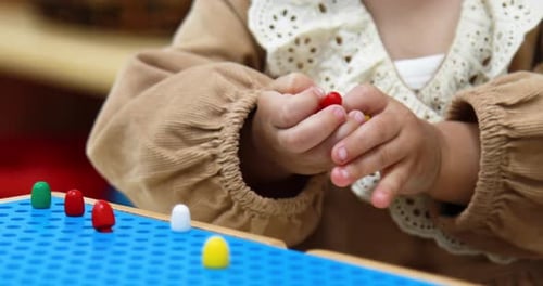 Child Playing with Colorful Pegs in Classroom
