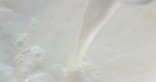 a hand pouring milk in slow motion in a special transparent cup milk and breakfast . concept of h
