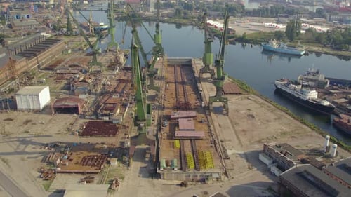 Fly Over Port Cranes At The Shipyard, Shipbuilding Industry In Gdansk, Poland. Aerial Drone Shot