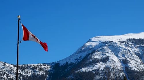 Canadian Flag Waving Against Snowy Mountain Landscape