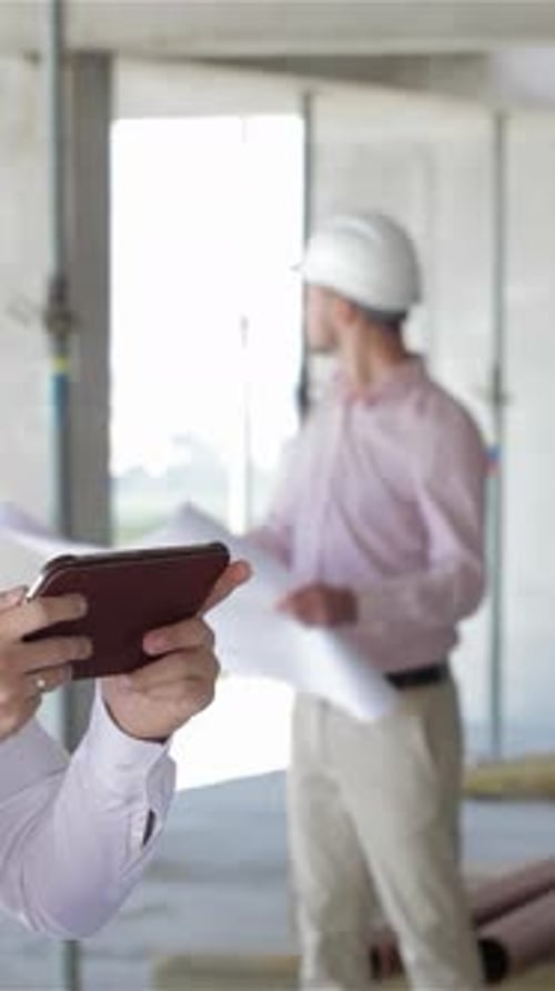 Confident Architect Examines Digital Tablet on Bustling Construction Site