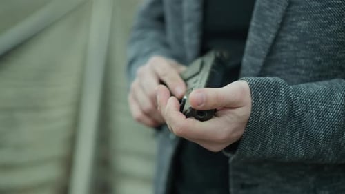 Close View of Man Handling Handgun Beside Railway Track