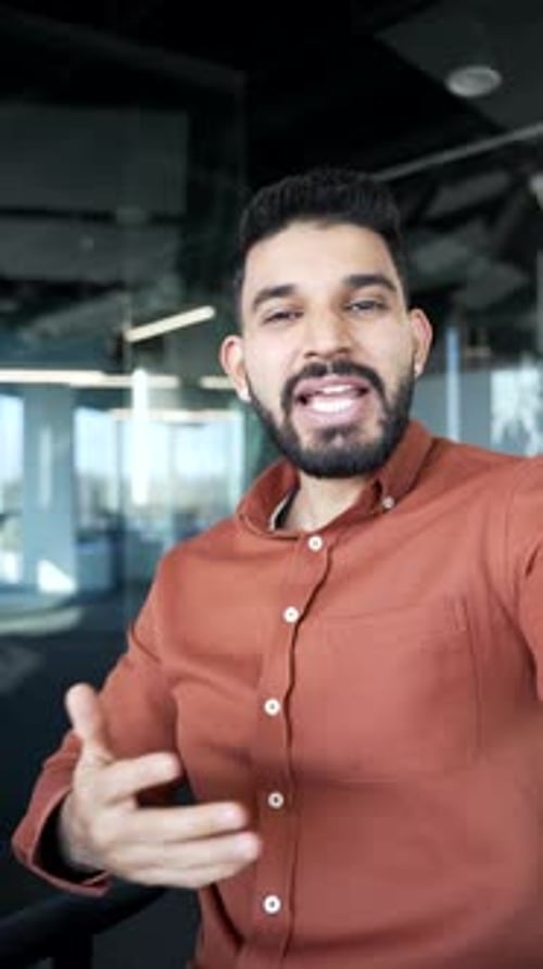 POV Vertical. Happy businessman talking on a video call using a phone in a modern office. Handsome
