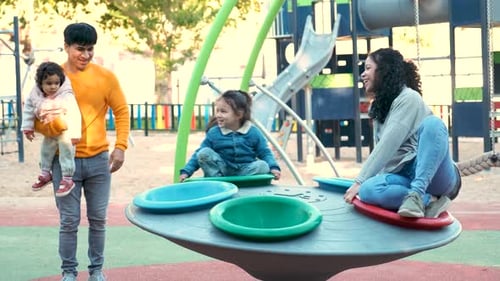 Latin Family with Two Children Playing Together in a Playground