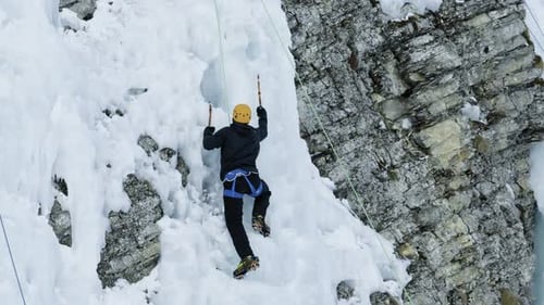 Ice climbing in famous Adelboden, Switzerland - climber ascending steep ice wall