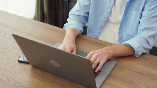 Person Typing on Laptop at Wooden Table