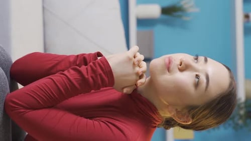 Vertical Video of Thoughtful and unhappy Asian woman sitting in living room.