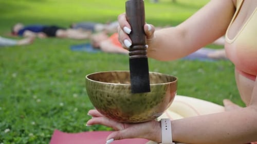 Closeup Woman Playing Singing Bowls During Yoga Meditation in City Park