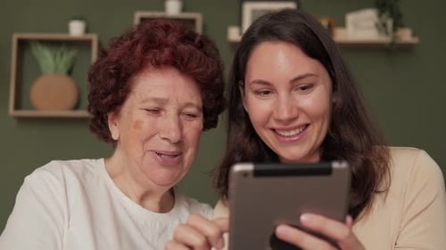 Senior Woman and Young Adult Looking at Tablet