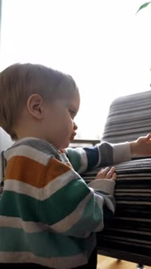 Vertical of Toddler Plays with Toys on Armchair