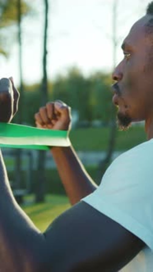 Young Adult Exercising Arms with Green Band in Park