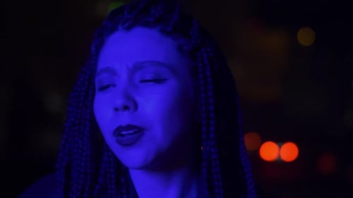 Woman Singing with Braids in Blue Night Lighting