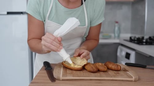 Woman Decorating Pastries With Cream in Kitchen