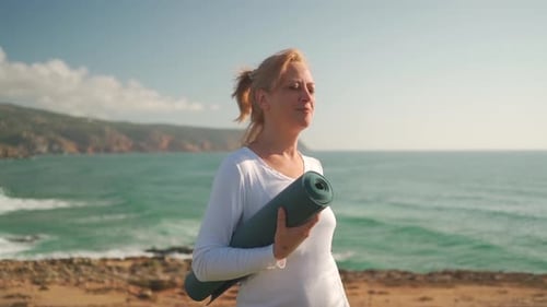 Senior Woman with Yoga Mat By Ocean