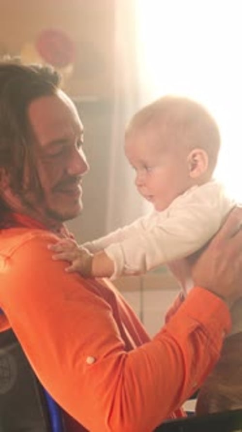 Dad in wheelchair holds baby, playing at home