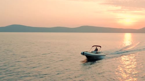Drohnenaufnahmen einer jungen Frau, die bei Sonnenuntergang ein Schnellboot fährt. Wunderschönes blaues Meer.