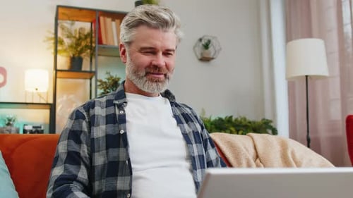 Man Works on Laptop at Home on Couch
