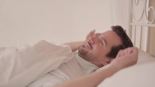 Side View of Young Man Waking Up and Leaving Bed