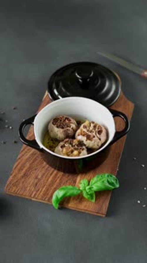Garlic bulbs Baked with olive oil and spices in black dish. Close-up