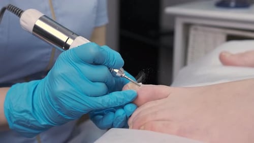 Manicurist Using Electric File on Client's Toenails