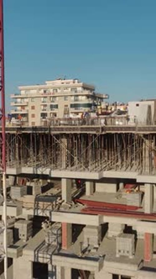Vertical Video of Residential Construction With Active Crane Work and Workers Pouring Concrete