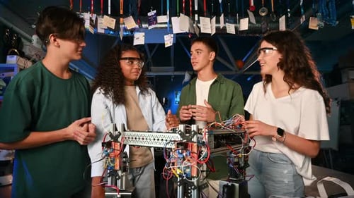 Group of young people discussing and doing experiments in robotics in a laboratory. Robot on the tab