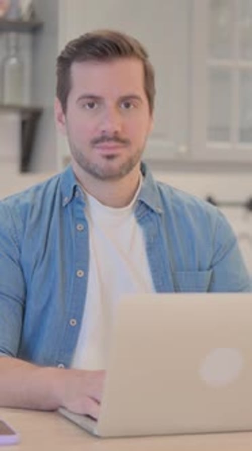 Man Smiling and Typing on Laptop at Home