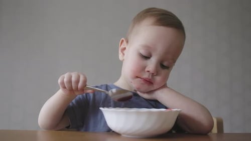 Little Baby Toddler Kid Eating Soup Using Spoon in Hand Learning Feed Himself