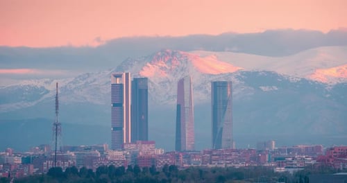 Timelapse of Madrid 5 towers skyline and snowy sierra mountain during sunrise