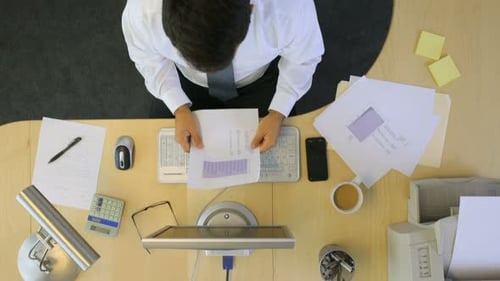 Overhead view of young professional businessman typing on laptop at modern office desk