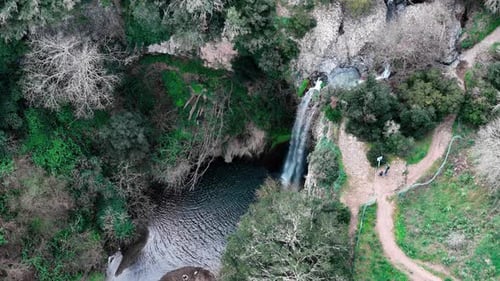 Breathtaking Aerial View of a Serene Waterfall Surrounded by Lush Greenery and Tranquil Pathways
