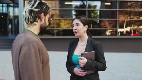 Adult businesswoman in suit talking to office colleague
