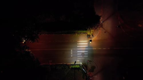 Aéreo. Un automóvil con los faros encendidos pasa por un paso de peatones por la noche. Vista desde arriba desde un dron