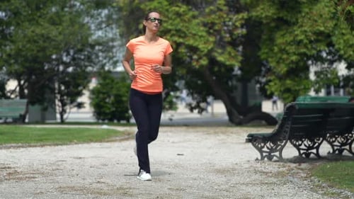 Young woman jogging in city park super slow motion fitness in nature