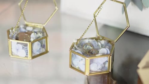 Two small golden boxes with white flowers, coins and wedding rings inside. Close-up. 4k. Slow motion