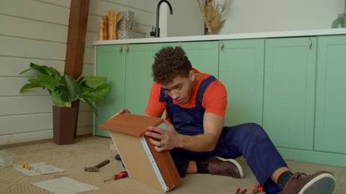 Un bricoleur noir positif termine l'assemblage d'un tiroir de table de chevet à faire soi-même