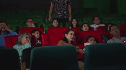 People Watch a Scary Movie in Darkened Cinema