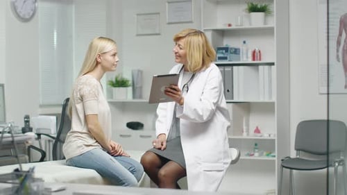 Doctor Explains Diagnosis to Woman in Examination Room