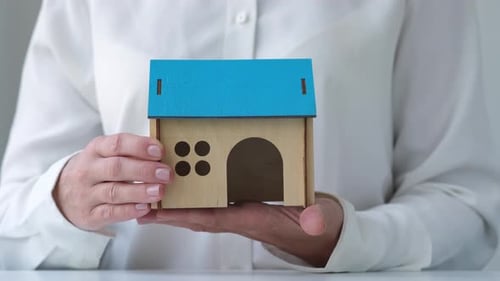 Person Holding Miniature House in Palms of Hands