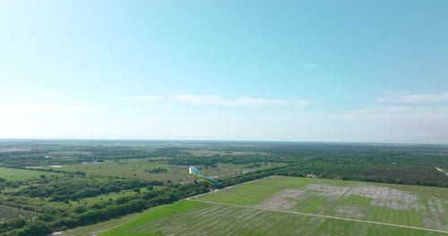 Hang Glider Soaring Over Green Rural Landscape
