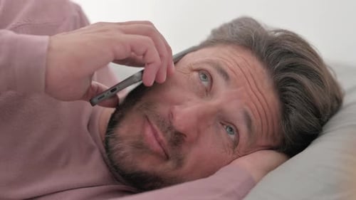 Close up of Man Talking on phone while Lying on Side in Bed