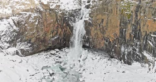 Majestic Waterfall Cascading On A Rocky And Snowy Terrain