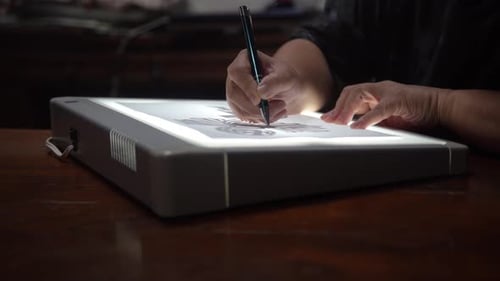 A woman copying a picture using a tracing table
