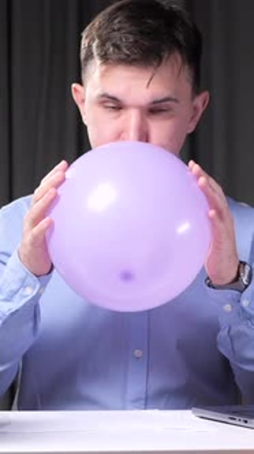 Vertical Video Office Worker Inflating Balloon at Desk to Relieve Stress