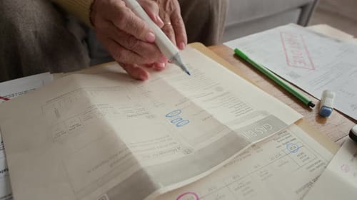 Senior Woman Highlights Bills at Home on Couch